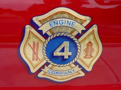 Exterior view of small fire truck showing cab, body compartments, and wheel/tire area.