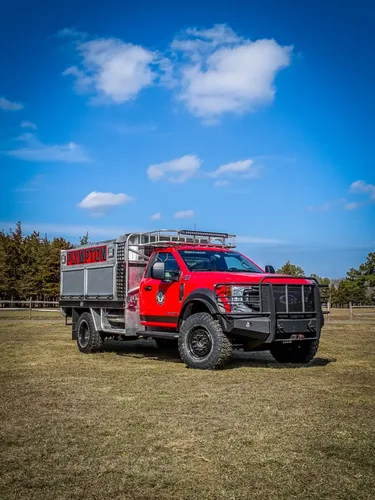 Exterior view of small fire truck showing cab, body compartments, and wheel/tire area.