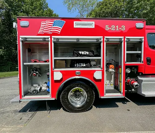 Exterior view of small fire truck showing cab, body compartments, and wheel/tire area.