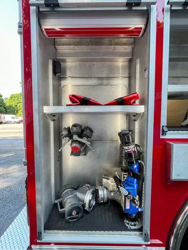Exterior view of small fire truck showing cab, body compartments, and wheel/tire area.