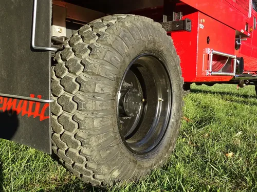 Exterior view of small fire truck showing cab, body compartments, and wheel/tire area.
