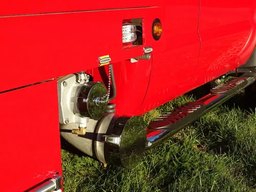Exterior view of small fire truck showing cab, body compartments, and wheel/tire area.