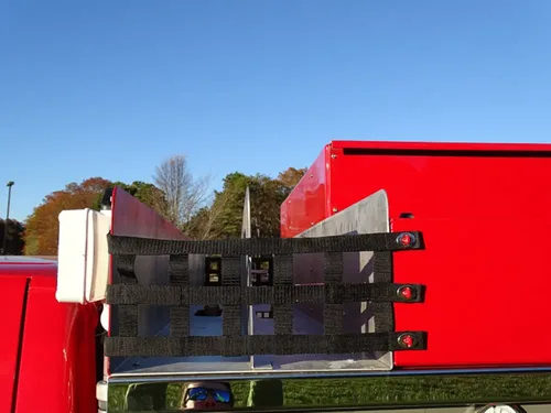 Exterior view of small fire truck showing cab, body compartments, and wheel/tire area.