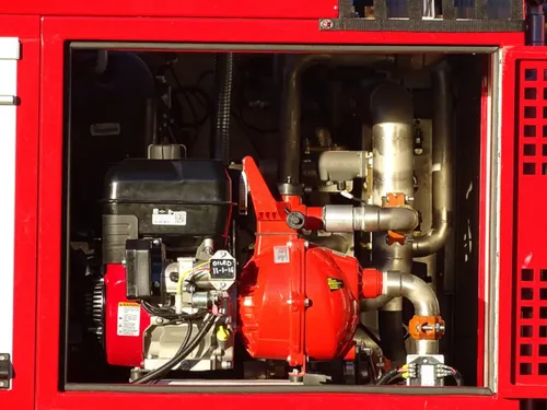 Exterior view of small fire truck showing cab, body compartments, and wheel/tire area.