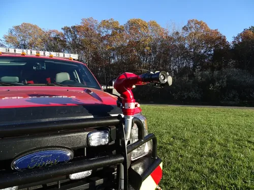 Exterior view of small fire truck showing cab, body compartments, and wheel/tire area.