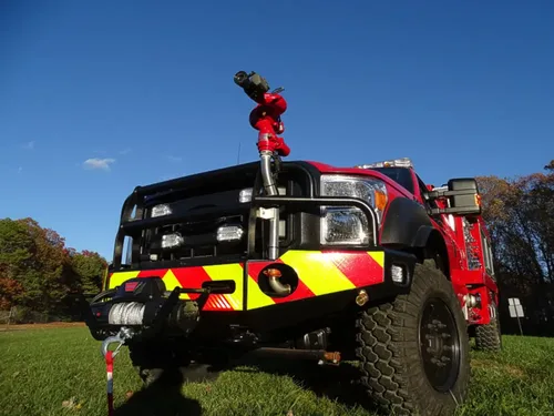 Exterior view of small fire truck showing cab, body compartments, and wheel/tire area.