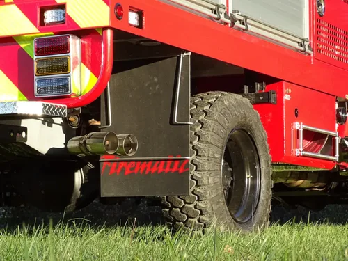 Exterior view of small fire truck showing cab, body compartments, and wheel/tire area.