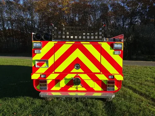 Exterior view of small fire truck showing cab, body compartments, and wheel/tire area.