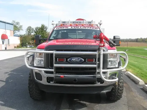 Exterior view of small fire truck showing cab, body compartments, and wheel/tire area.