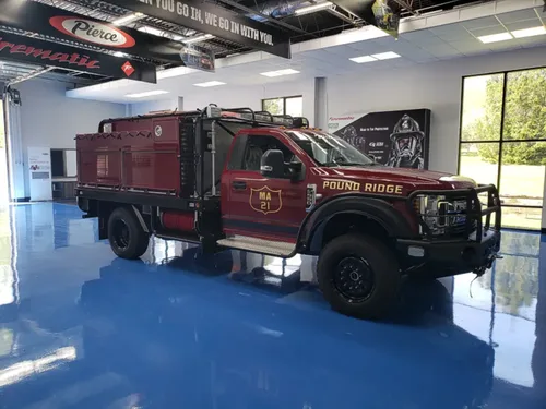 Exterior view of small fire truck showing cab, body compartments, and wheel/tire area.