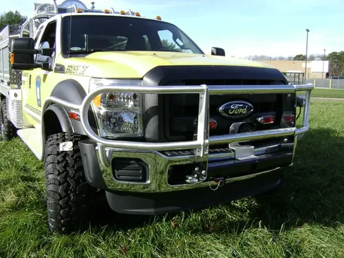 Exterior view of small fire truck showing cab, body compartments, and wheel/tire area.