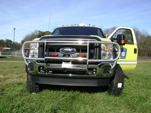 Exterior view of small fire truck showing cab, body compartments, and wheel/tire area.