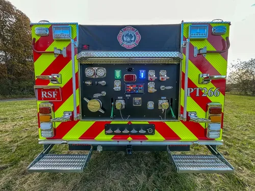 Exterior view of small fire truck showing cab, body compartments, and wheel/tire area.