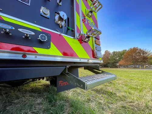 Exterior view of small fire truck showing cab, body compartments, and wheel/tire area.