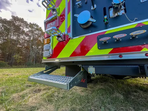 Exterior view of small fire truck showing cab, body compartments, and wheel/tire area.