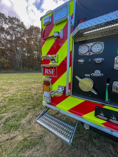 Exterior view of small fire truck showing cab, body compartments, and wheel/tire area.