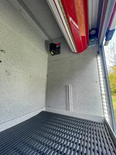 Exterior view of small fire truck showing cab, body compartments, and wheel/tire area.