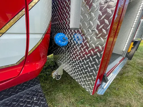 Exterior view of small fire truck showing cab, body compartments, and wheel/tire area.
