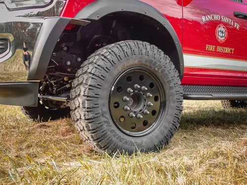 Exterior view of small fire truck showing cab, body compartments, and wheel/tire area.