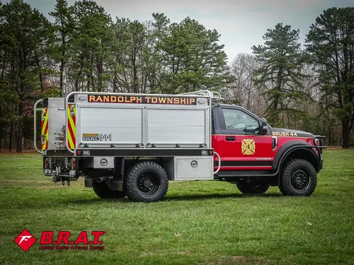 Exterior view of small fire truck showing cab, body compartments, and wheel/tire area.