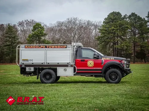 Exterior view of small fire truck showing cab, body compartments, and wheel/tire area.