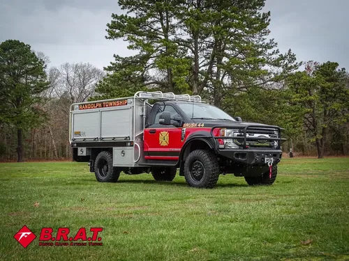 Exterior view of small fire truck showing cab, body compartments, and wheel/tire area.
