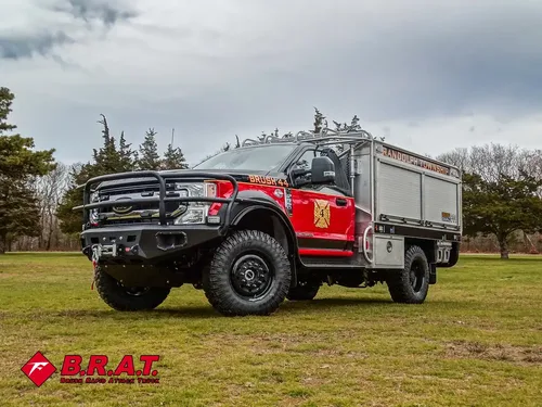 Exterior view of small fire truck showing cab, body compartments, and wheel/tire area.