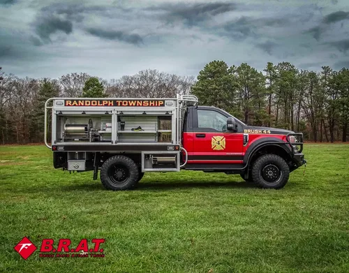 Exterior view of small fire truck showing cab, body compartments, and wheel/tire area.