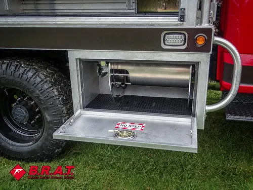 Exterior view of small fire truck showing cab, body compartments, and wheel/tire area.