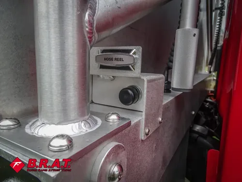 Exterior view of small fire truck showing cab, body compartments, and wheel/tire area.