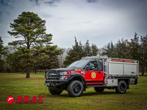 Exterior view of small fire truck showing cab, body compartments, and wheel/tire area.