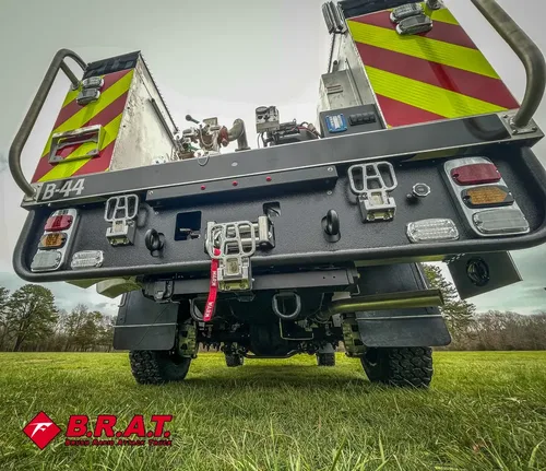 Exterior view of small fire truck showing cab, body compartments, and wheel/tire area.