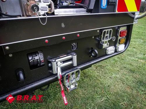 Exterior view of small fire truck showing cab, body compartments, and wheel/tire area.