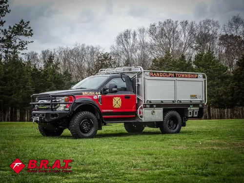 Exterior view of small fire truck showing cab, body compartments, and wheel/tire area.