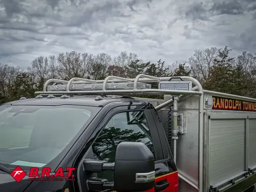 Exterior view of small fire truck showing cab, body compartments, and wheel/tire area.