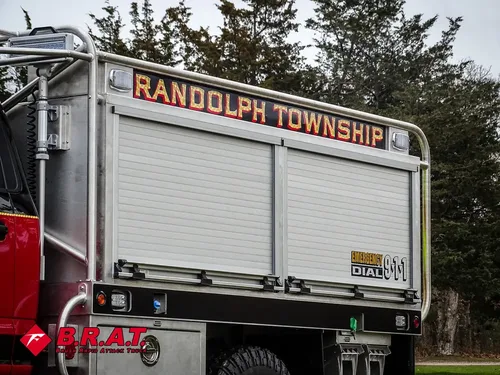 Exterior view of small fire truck showing cab, body compartments, and wheel/tire area.