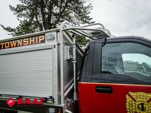 Exterior view of small fire truck showing cab, body compartments, and wheel/tire area.