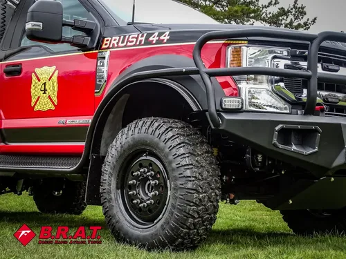 Exterior view of small fire truck showing cab, body compartments, and wheel/tire area.