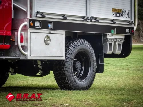 Exterior view of small fire truck showing cab, body compartments, and wheel/tire area.