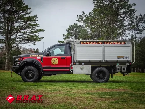 Exterior view of small fire truck showing cab, body compartments, and wheel/tire area.
