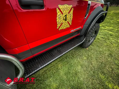 Exterior view of small fire truck showing cab, body compartments, and wheel/tire area.