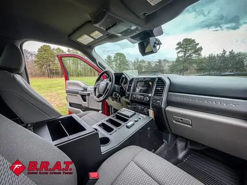 Exterior view of small fire truck showing cab, body compartments, and wheel/tire area.
