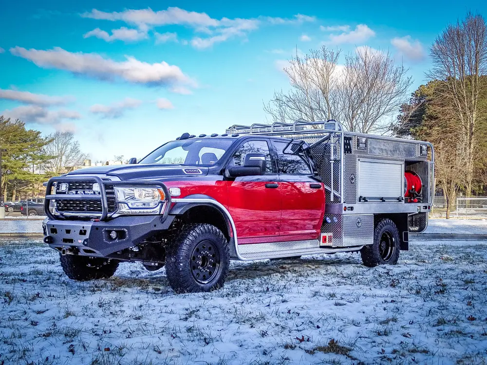 Front-left three-quarter exterior view of the red brush truck parked on snowy ground.