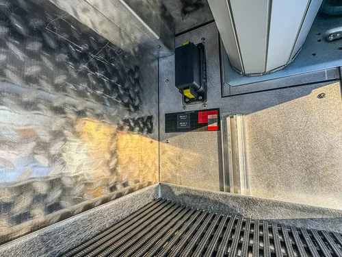 Interior close-up of a utility compartment with wiring and mounted components.