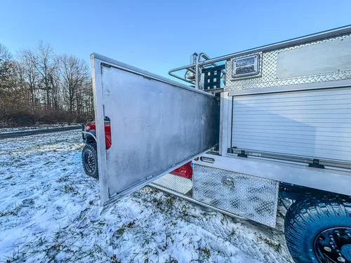 Side view with a long utility-body compartment door fully opened.