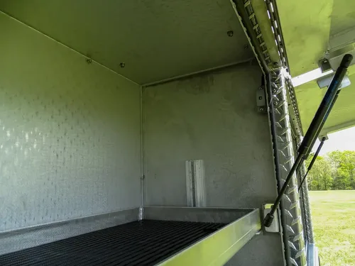 Exterior view of small fire truck showing cab, body compartments, and wheel/tire area.