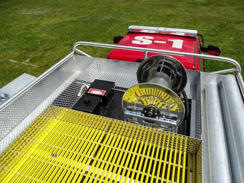 Exterior view of small fire truck showing cab, body compartments, and wheel/tire area.