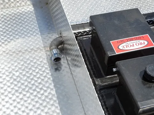 Exterior view of small fire truck showing cab, body compartments, and wheel/tire area.