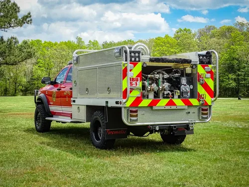 Exterior view of small fire truck showing cab, body compartments, and wheel/tire area.