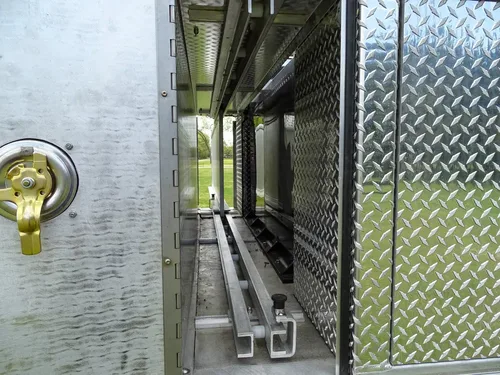 Exterior view of small fire truck showing cab, body compartments, and wheel/tire area.